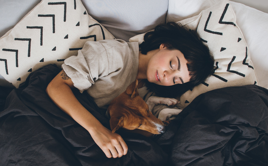 lady sleeping with a dog in her bed