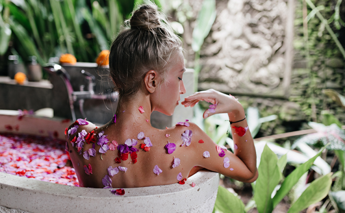 spa treatment woman in a bathtub with floral petals