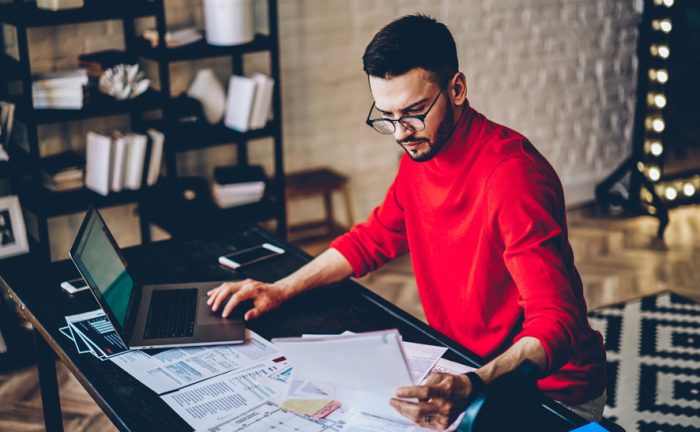 man in a red sweater sitting by a desk